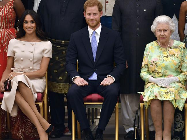 FILE - In this Tuesday, June 26, 2018 file photo Britain's Queen Elizabeth, Prince Harry and Meghan, Duchess of Sussex pose for a group photo at the Queen's Young Leaders Awards Ceremony at Buckingham Palace in London. In a stunning declaration, Britain's Prince Harry and his wife, Meghan, said they are planning "to step back" as senior members of the royal family and "work to become financially independent." A statement issued by the couple Wednesday, Jan. 8, 2020 also said they intend to "balance" their time between the U.K. and North America. (John Stillwell/Pool Photo via AP, File)