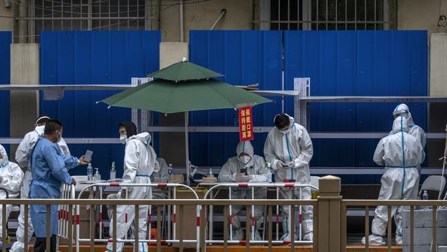 Workers wear protective suits as they control the entrance area for deliveries and supplies around a community under lockdown. Picture: Getty Images.