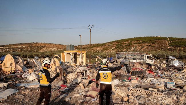 Members of the Syrian Civil Defence (White Helmets) survey the area following a Russian air strike, at a camp for those displaced by conflict on the outskirts of the rebel-held village of al-Hamamah in the district of Jisr al-Shughur in thr west of Syria's northwestern Idlib province on October 24, 2023. (Photo by AAREF WATAD / AFP)