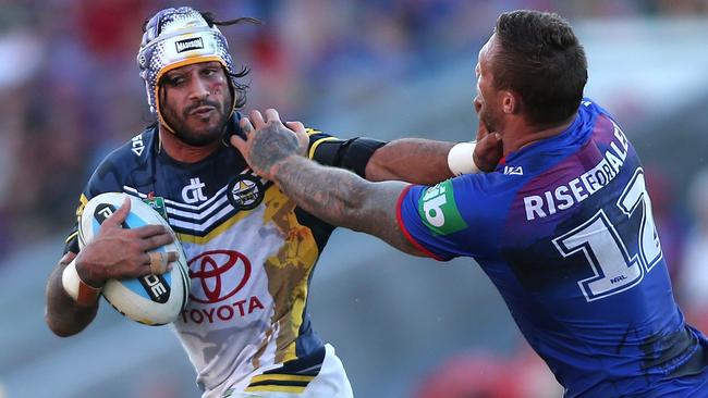 Cowboys captain Johnathan Thurston is tackled by Tariq Sims of the Knights at Hunter Stadium.