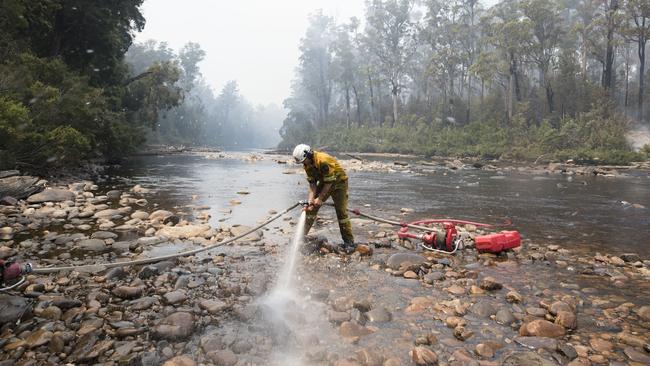 Luke Mellers, Hobart Fire Brigade RAT Team, pumps water out of the Huon River to fight a fire spreading into the Huon Pine Walk, Tahune area. Picture: WARREN FREY/TFS