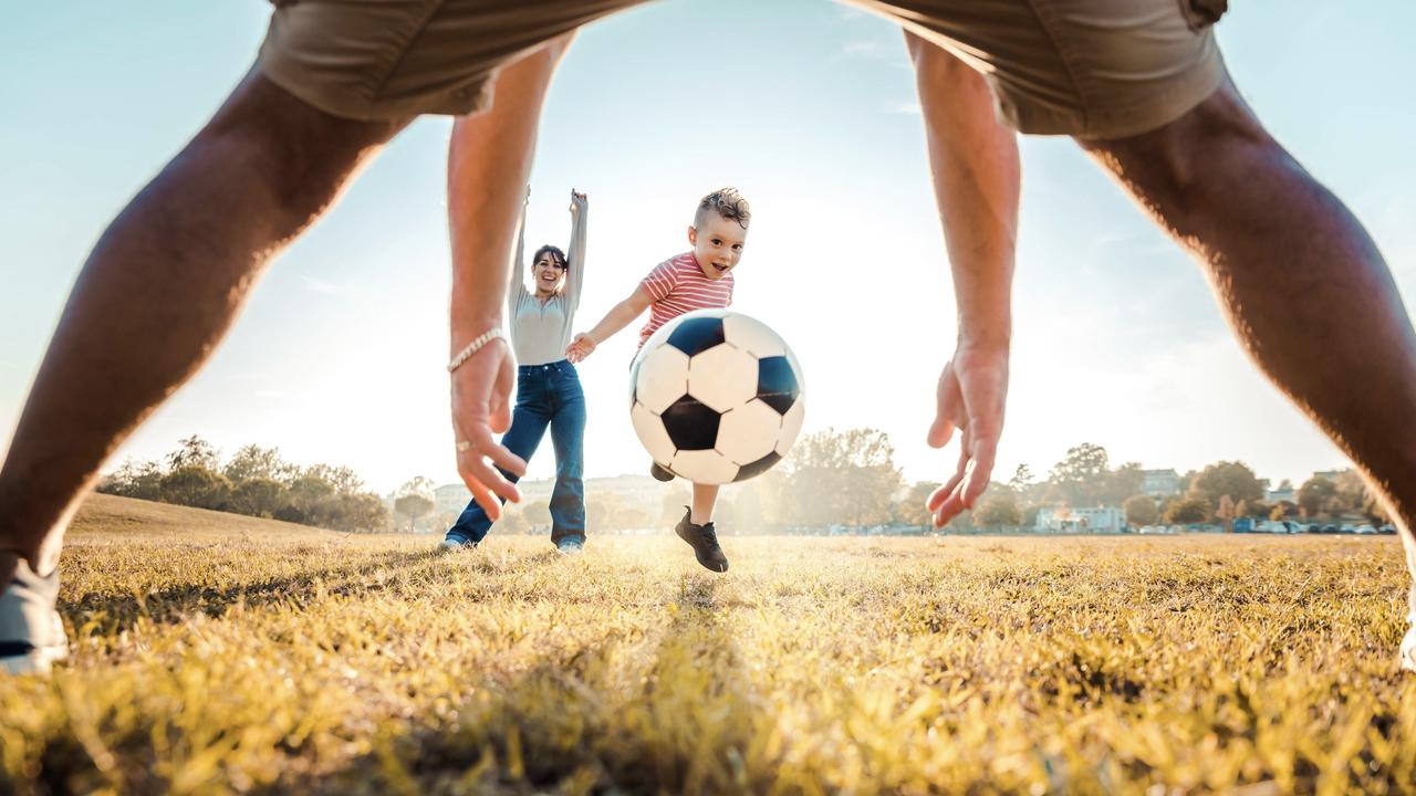 A young boy kicks a ball while playing with his family. Only 50 per cent of parents spend 1-3 hours a week playing outdoors with their kids. Picture: iStock