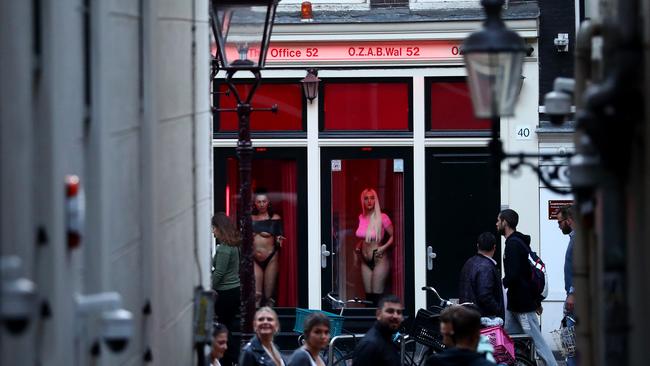 Prostitutes stand behind windows in Amsterdam’s red light district.