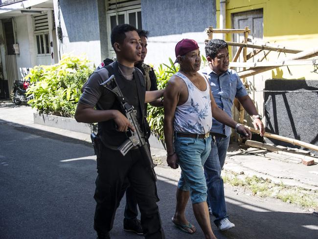 Police take a man in for questioning as they patrol around the Surabaya police headquarters following a suicide attack in Surabaya. Picture: AFP