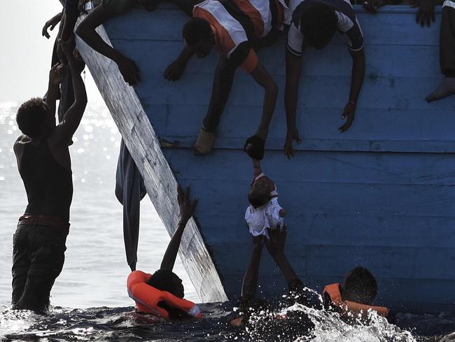 Migrants try to pull a child out of the water as they wait to be rescued by members of Proactiva Open Arms NGO in the Mediterranean sea, some 12 nautical miles north of Libya, on October 4, 2016. Picture: AFP PHOTO / ARIS MESSINIS