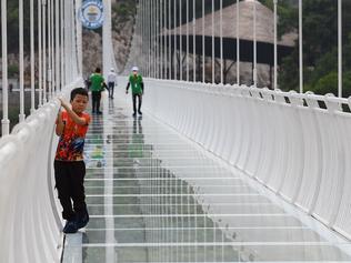 TOPSHOT - A young visitor makes his way across the Bach Long glass bridge in Moc Chau district in Vietnam's Son La province on April 29, 2022. - Vietnam launched a new attraction for tourists -- with a head for heights -- on April 29 with the opening of a glass-bottomed bridge suspended some 150 metres above a lush, jungle-clad gorge. (Photo by Nhac NGUYEN / AFP)