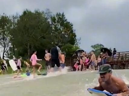 Boogie boarders skid down a waterlogged hill.