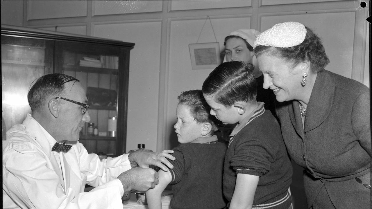 First shots of the Salk anti-polio vaccine being given by Health and Medical Services deputy director Dr DW Johnson in Brisbane in 1956. On the receiving end are Clem, 7, left, and Paul, 9, sons of the Premier Vince Gair, pictured with their mother. Picture: Bob Millar Jnr