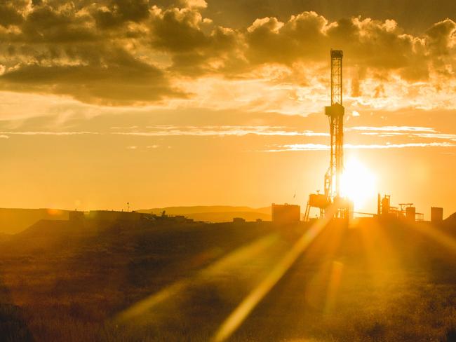 Dusk or Dawn image of a fracking drilling rig under a beautiful cloudscape and dreamy golden light