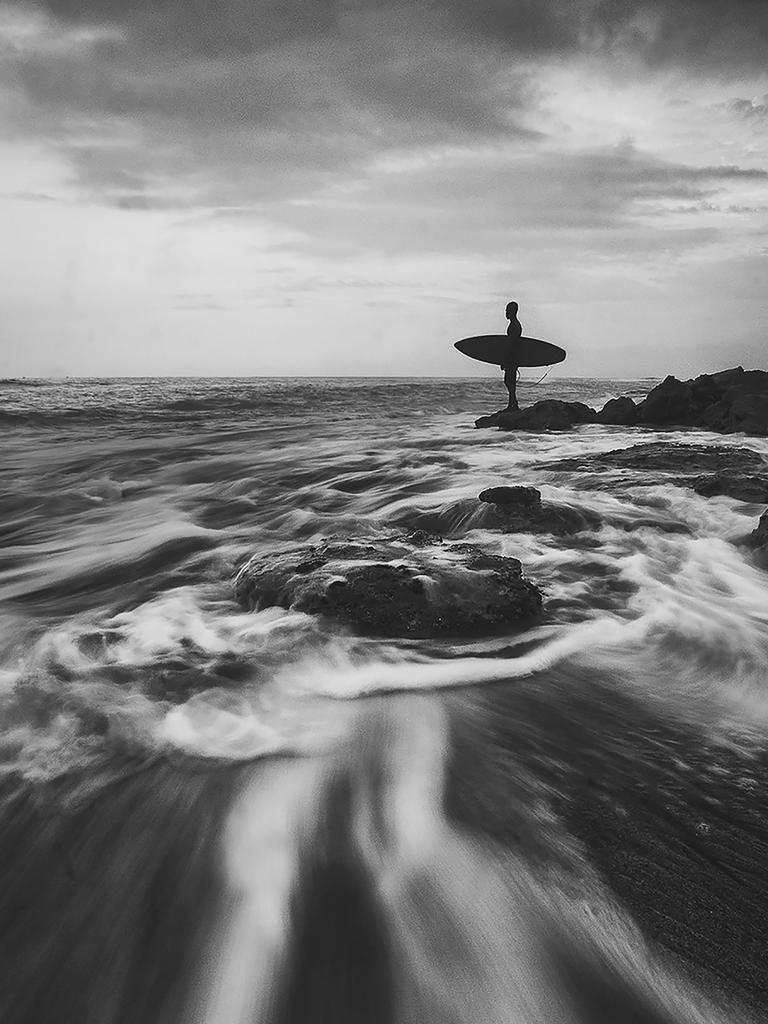 Image Name: Waves of Life Photographer Name: Sandaru Saranjaya Gayanpriya Urala Liyanage Year: 2018 Image Description: This was capture in a rainy evening at Koggala beach, southern province Sri Lanka, the person who is in this image is a teenage son of a fisherman,he helps out all day with his fathers work and evening e enjoys surfing. I wanted to emphasis for this image, The struggle of life around him and how he happily overcomes those and looks at the in a calm look. Copyright: Sandaru Saranjaya Gayanpriya Urala Liyanage, Winner, Sri Lanka National Award. Picture: Sony World Photography Awards/ Sandaru Saranjaya