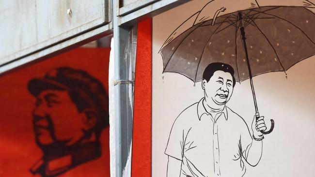 Posters of Mao Zedong, left, and the Chinese President at a Beijing market last month. Picture: AFP
