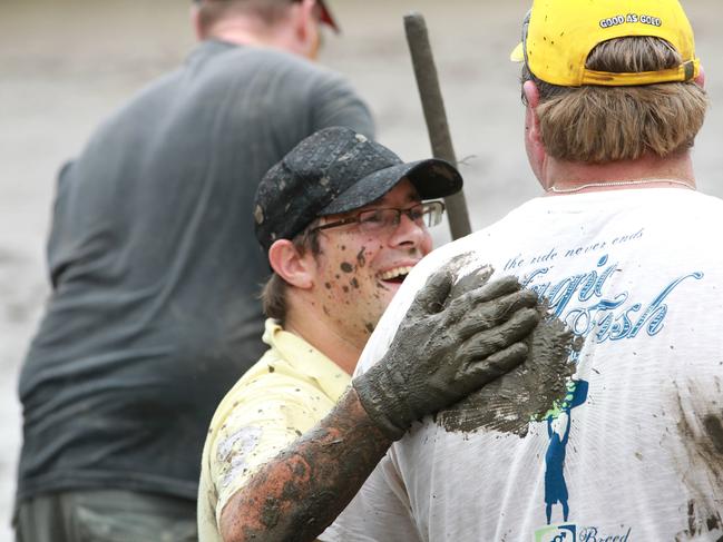 Brisbane flood clean-up. An army of people from Gold Coast businesses pitch in with mud up to their knees to clean out a property on Avebury St, West End. (L-R) Dave Jeffrey gives Mark Hobbs a pat on the back.