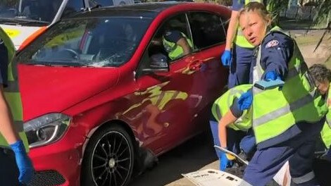 Emergency workers assist Lorraine Gooden after she was hit by the red Mercedes while she walked on the footpath on Pringle Ave, Belrose. Picture: Supplied