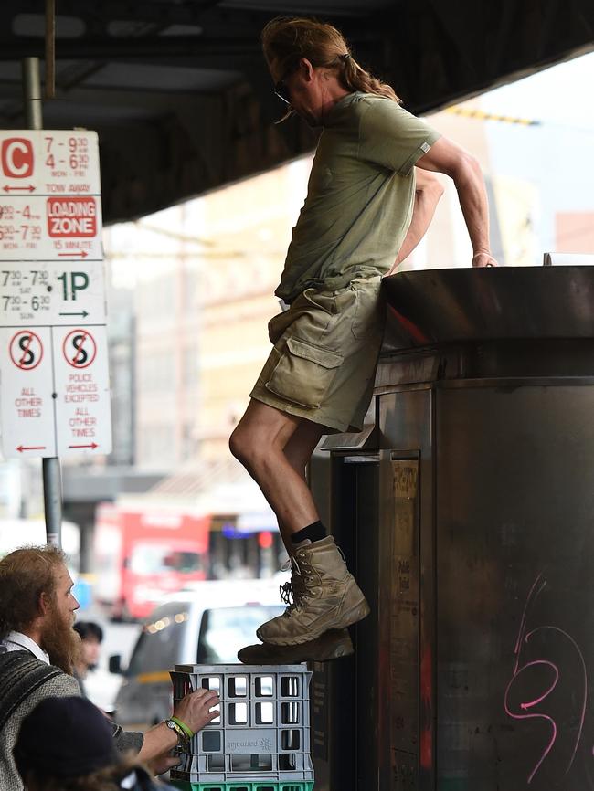 A man climbs down from the public toilet after having a sleep on the roof. Picture: Nicole Garmston