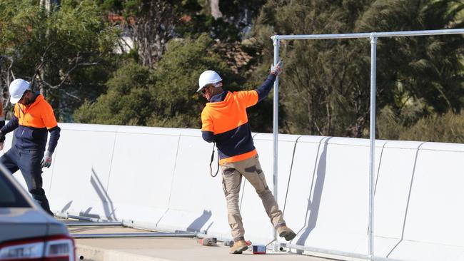 Construction workers assemble temporary screens on the Honeypot Rd bridge in July. Picture: AAP Image/Russell Millard