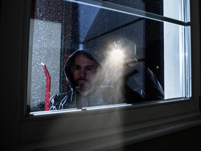 Burglar With Crowbar And Flashlight Looking Into A House Windows