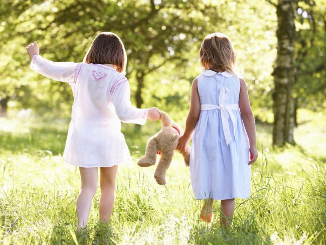 Two Young Girls Walking Through Summer Field Carrying Teddy Bear. Childhood innocence. Thinkstock