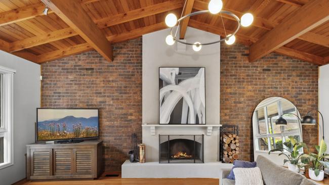 An open fireplace, vaulted ceilings, exposed beams and brickwork in one of the living areas.