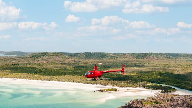 Helicopter flying over the beach and bay on the western side of the tip of Australia. Photo: TEQ