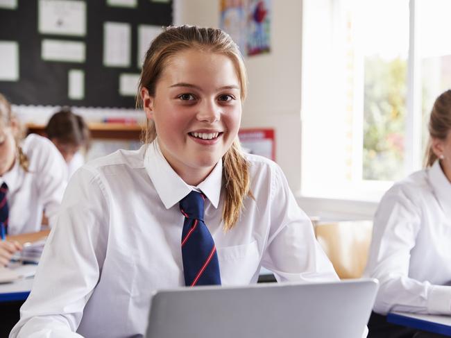 Portrait Of Female Pupil In Uniform Using Laptop In Classroom