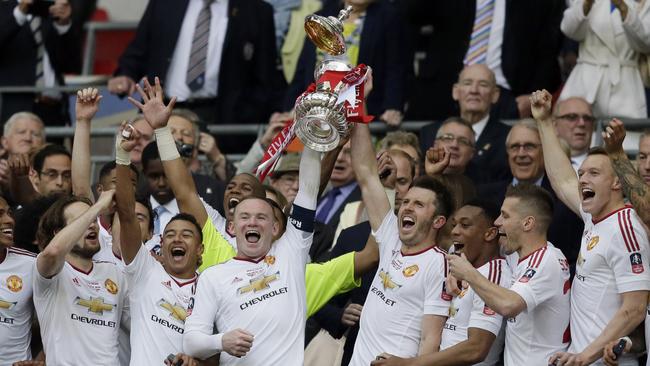 Manchester United’s Wayne Rooney, center left, and Michael Carrick lift the trophy.