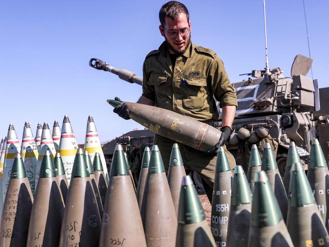 An Israeli soldier carries a 155mm artillery shell near a self-propelled howitzer deployed at a position near the border with Lebanon in the upper Galilee region of northern Israel on October 18, 2023. Israeli troops killed four militants attempting to infiltrate from Lebanon, the army said on October 17, as tensions run high along the border between the two countries. (Photo by Jalaa MAREY / AFP)