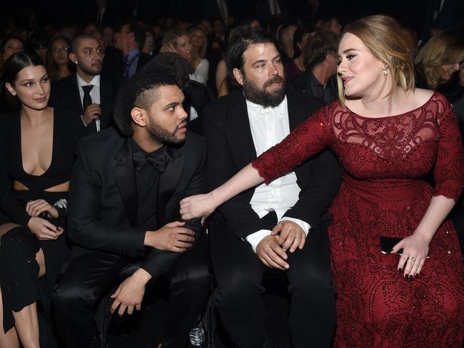 Adele, next to then-husband Simon Konecki, greets singer The Weeknd at the Grammys in 2016. Picture: Getty Images/AFP