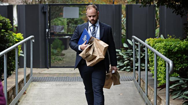 A detective leaving the apartment block with evidence bags on Thursday. Picture: Adam Yip