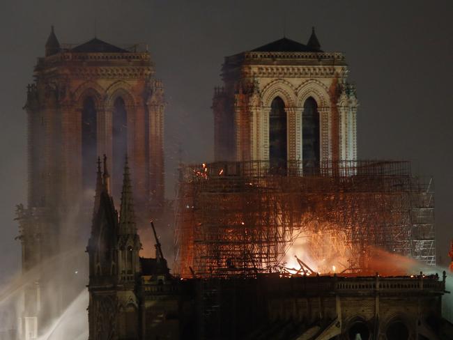 Firefighters tackle the blaze as flames and smoke rise from Notre Dame cathedral as it burns in Paris, Monday, April 15, 2019. Massive plumes of yellow brown smoke is filling the air above Notre Dame Cathedral and ash is falling on tourists and others around the island that marks the center of Paris. (AP Photo/Thibault Camus)
