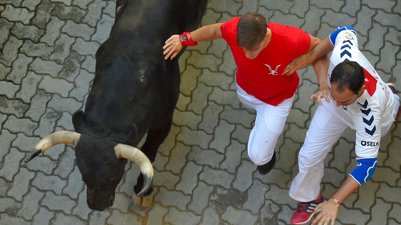 Participants run next to a fighting bull on the sixth bull run of the San Fermin festival in Pamplona, northern Spain. Picture: AFP