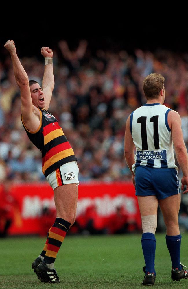 Darren Jarman celebrates as North’s Glenn Archer trudges away. Jarman kicked five for the day.