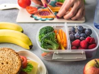 Mother giving healthy lunch for school hands