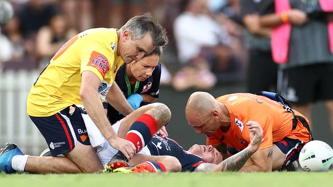 Jake Friend of the Roosters is attended to by team trainers after head knock