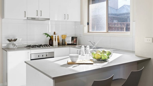 A stone-bench breakfast bar adjoins the well-appointed kitchen boasting a stainless-steel gas cooktop, electric oven, dishwasher and tiled splashback.