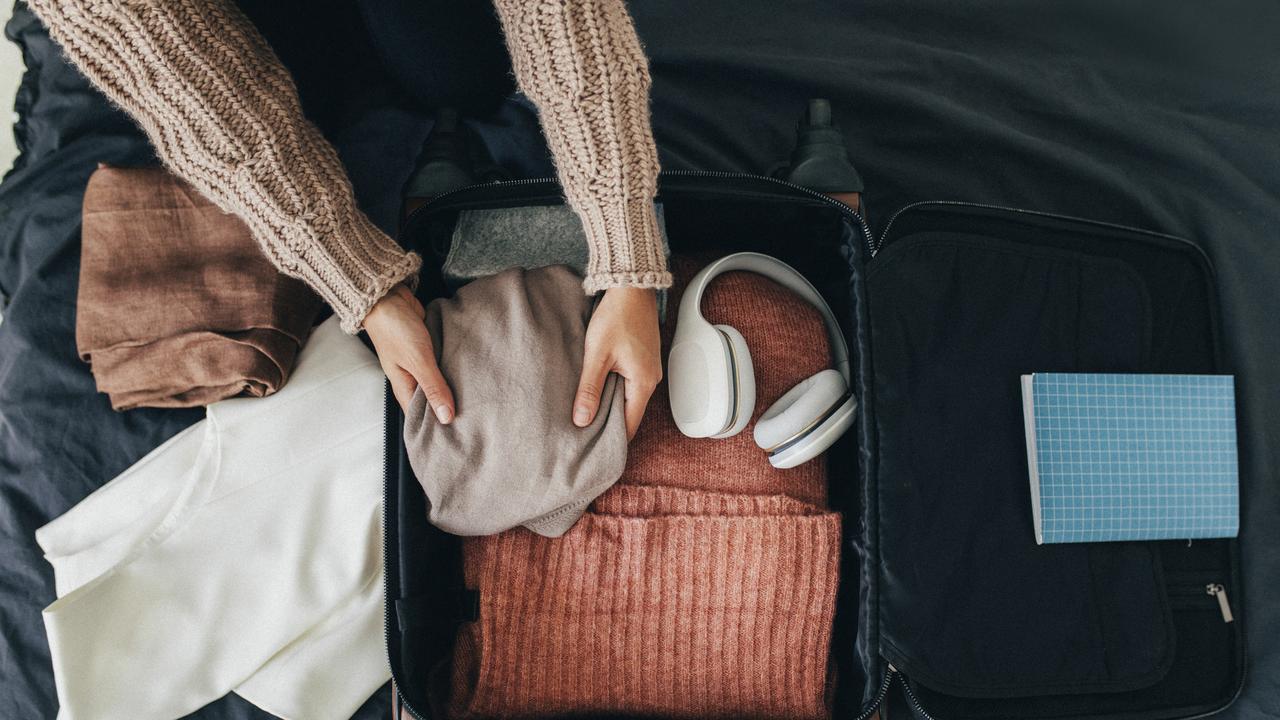 Happy traveller: a woman packing her clothes into a suitcase, getting ready for a trip.