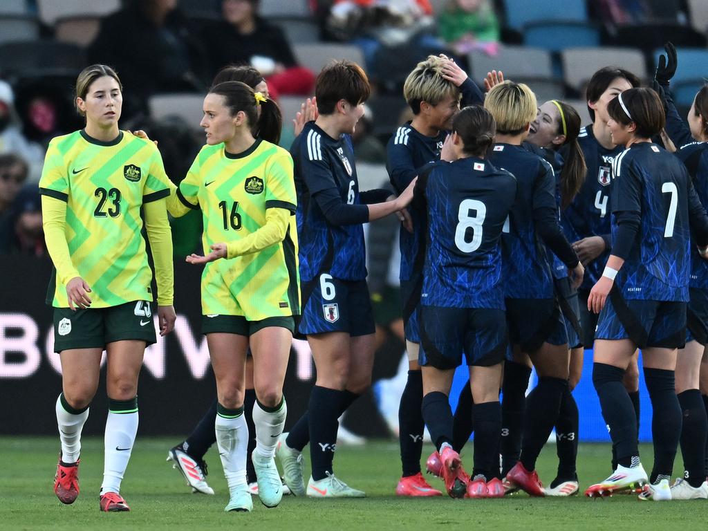 Matildas teammates Kyra Cooney-Cross (left) and Hayley Raso look dejected as Japan players celebrate one of their team’s four goals on Friday. Picture: Jack Gorman / Getty Images North America / Getty Images via AFP