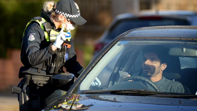 A police officer speaks to a driver at a roadblock in Camp Rd, Broadmeadows on the first morning that the area is officially locked down due to an increased rate of COVID-19 infections. Picture: Andrew Henshaw