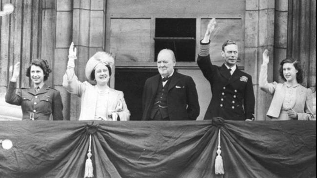 The prime minister Winston Churchill looks on, as King George VI, Queen Elizabeth, Princess Elizabeth (left) and Princess Margaret, wave to crowds gathered below, from the balcony of Buckingham Palace on VE Day, May 8, 1945.