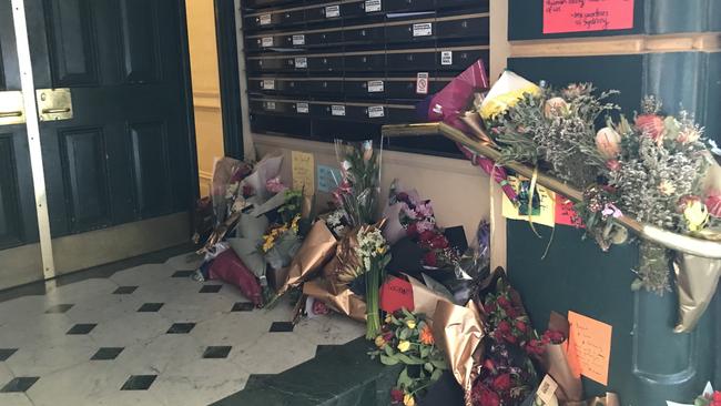 Flowers and handwritten notes left at the entry to the block where Michaela Dunn was found dead.