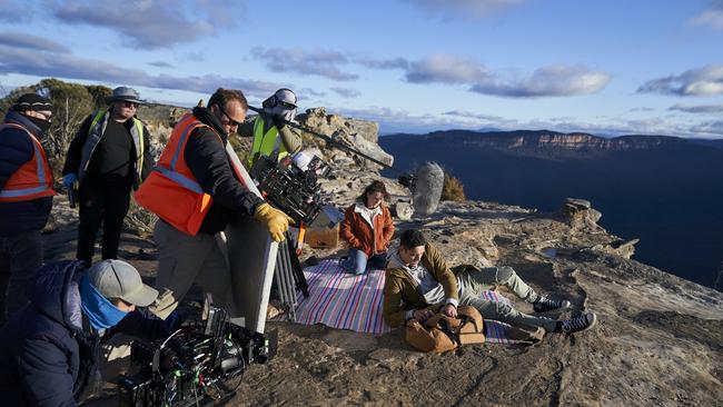 Cast and the crew on a rock ledge at the mountains.