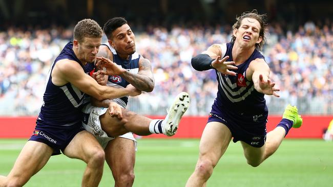 Tim Kelly of the Cats kicks forward under pressure from Sam Switkowski and Nat Fyfe of the Dockers during the Round 20 AFL match between the Fremantle Dockers and the Geelong Cats at Optus Stadium in Perth, Saturday, August 3, 2019.  (AAP Image/Gary Day) NO ARCHIVING, EDITORIAL USE ONLY