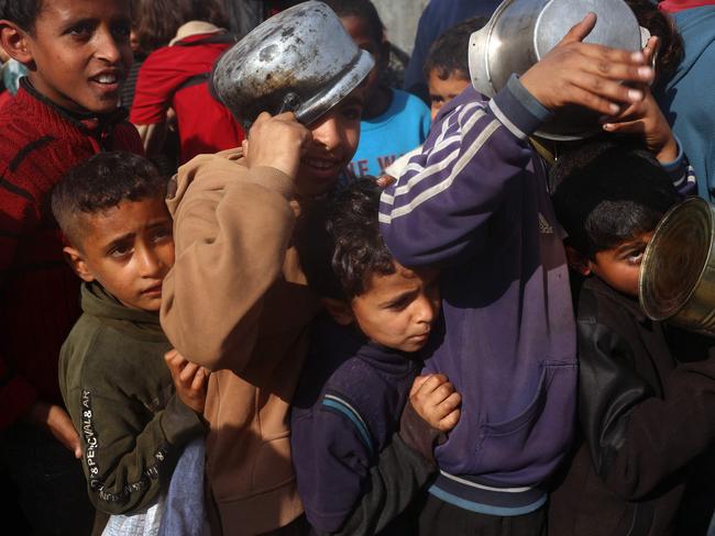 Palestinian children gather to receive aid food being distributed in the Deir al-Balah in the central Gaza Strip on January 16, 2025, following the announcement of a truce amid the ongoing war between Israel and Hamas. (Photo by Eyad BABA / AFP)