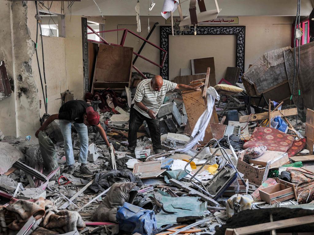 Palestinian males inspect items to be salvaged from a destroyed school run by the United Nations Relief and Works Agency for Palestine Refugees in the Near East at the Shati camp for Palestinian refugees, west of Gaza City. Picture: AFP