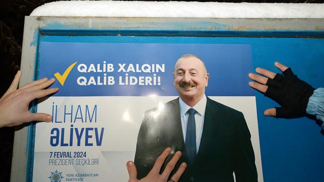 Electoral officials stick up a campaign poster of Azerbaijani president and presidential candidate Ilham Aliyev in Baku this week. Picture: Tofik Babayev/AFP