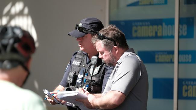 Police speak with a witness after the alleged stabbing murder at Cairns Central. September 22, 2021.