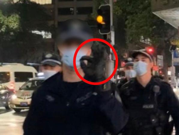 The police officer appearing to flash a white power symbol in Sydney last night. Picture: Supplied