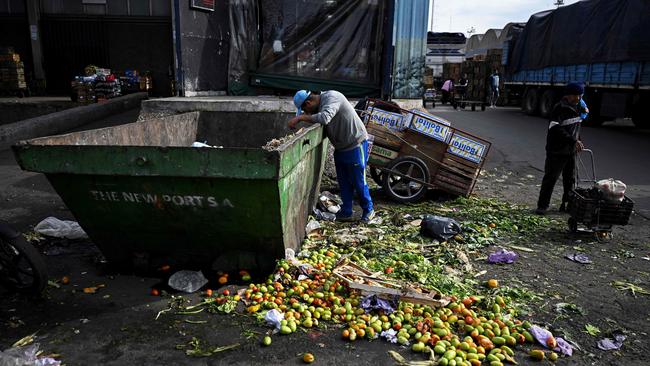 TOPSHOT - A man searches food inside a trash can where discarded fruits and vegetables are deposited at the Central Market in Buenos Aires, on May 12, 2023. Argentina's National Institute of Statistics and Census announced that April's Consumer Price Index rate increased 8.4% compared to March. (Photo by Luis ROBAYO / AFP)