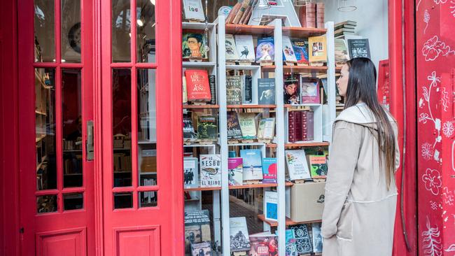 Young woman looking books on library showcase