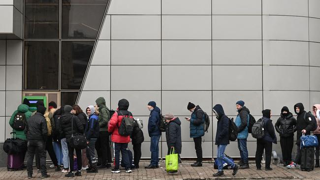 People withdraw money at a cash dispenser in Kyiv as air raid sirens rang out. Picture: AFP