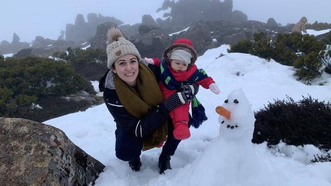 Kym Nissen and Evie Izatt with a snow man. After the road to the top of Mt Wellington was cleared hundreds of locals hit the snow.